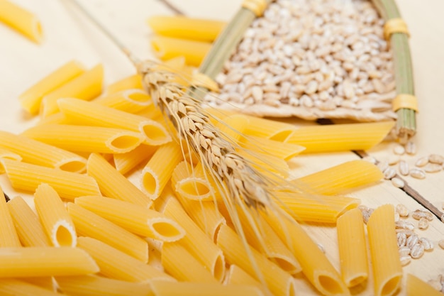 Photo wheat grain and raw pasta on table