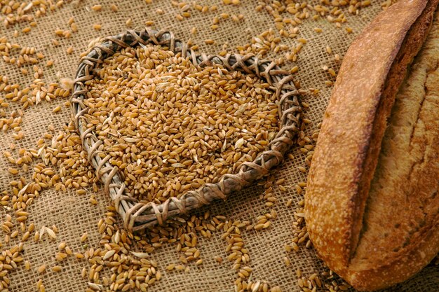 The wheat grain on sackcloth with homemade bread and heart shape figure as a symbol of a glutenfree