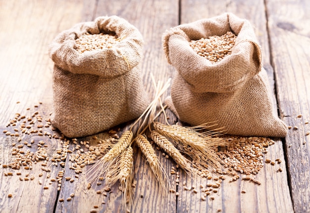 Wheat grains in sacks on wooden table