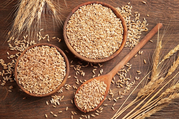 Wheat in kitchenware on wooden table