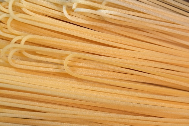 Wheat spaghetti long light yellow raw lie in the kitchen close-up