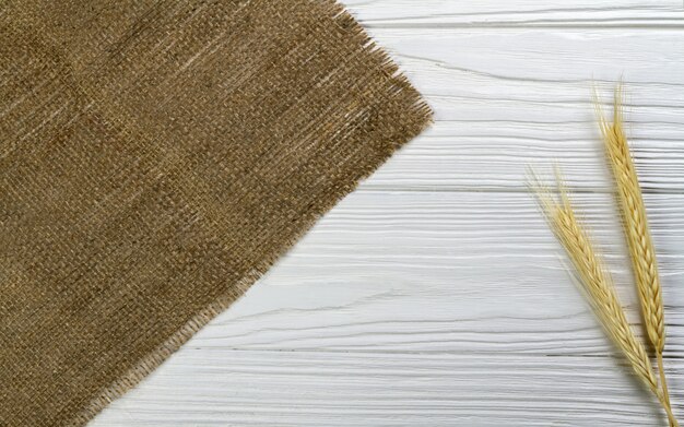 Фото Стебель пшеницы и гессиана ткань на белом деревянном столе