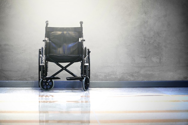 Photo wheel chair in hospital on raw cement background with light.