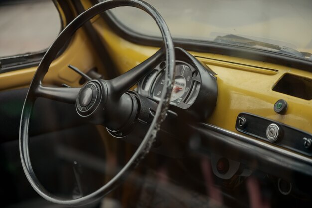 Wheel and control panel of old yellow car