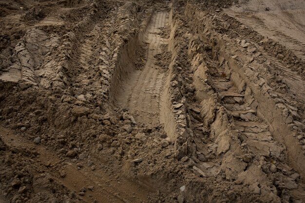 Wheel trail on sandy ground from large transport, tractor on construction site, sandy road. High quality photo