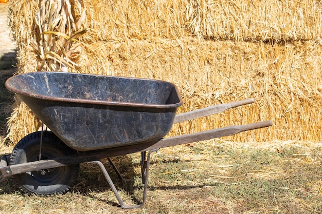 wheelbarrow in front of a stack or bale of hay on a farm