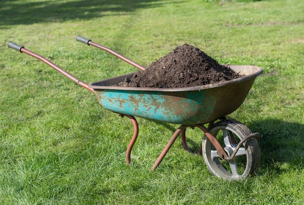 Photo wheelbarrow  full of compost on lawn