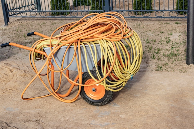 Wheelbarrow with electric cables and water hoses. Preparation for work. Moving loads at the construction site.