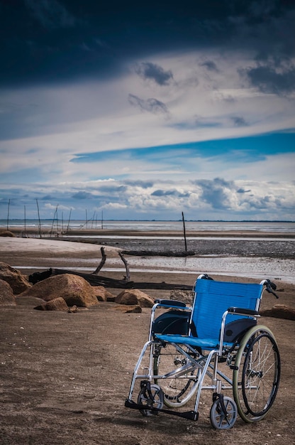wheelchair on beach against cloudy sky