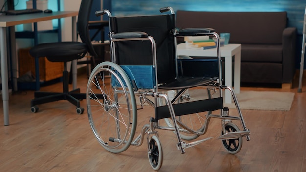 Инвалидная коляска в пустом пространстве, используемая кем-то с ограниченными физическими возможностями дома. Никто в гостиной с оборудованием для оказания транспортной поддержки и помощи в решении хронических проблем.