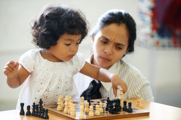 When did she get this smart. A cute little girl playing chess while her mom looks on.