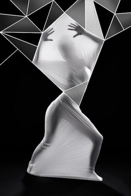 When trapped by your reality let your imagination free you Studio shot of a woman wrapped in fabric and surrounded by geometric shapes against a black background