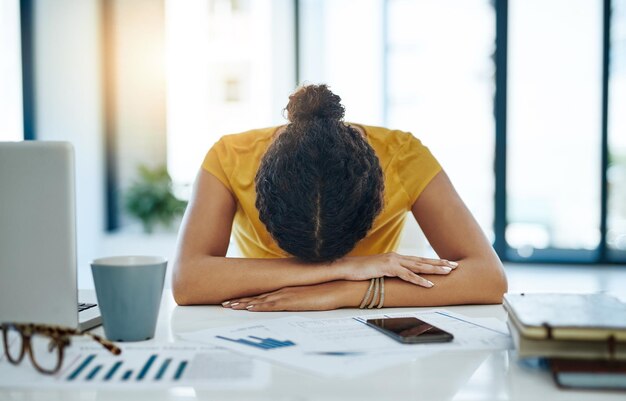 When will this day end Shot of a young designer with her head down on her office desk