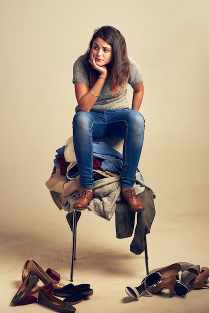 When you cant find an outfitnothing makes sense anymore Studio shot of a young woman trying to choose an outfit from a pile of clothes against a brown background