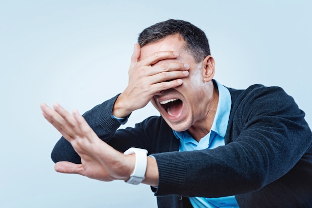 Where am I. Nervous man getting stressed while keeping his hand on eyes and trying to find the right way over the background.