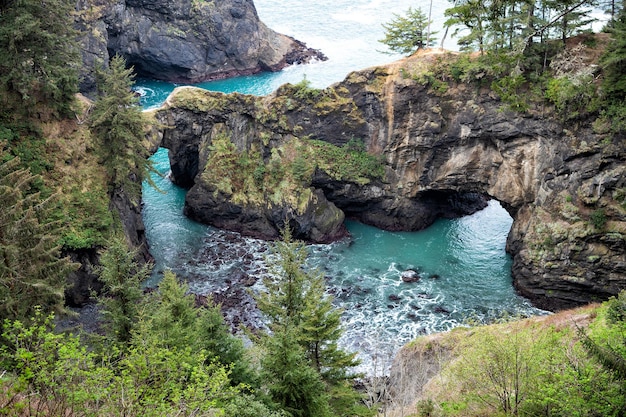 Where rocky coastline jut out into sea. Sea arches and coastal inlets. Rocky coast in Oregon, USA. Arch rocks between jagged cliffs.