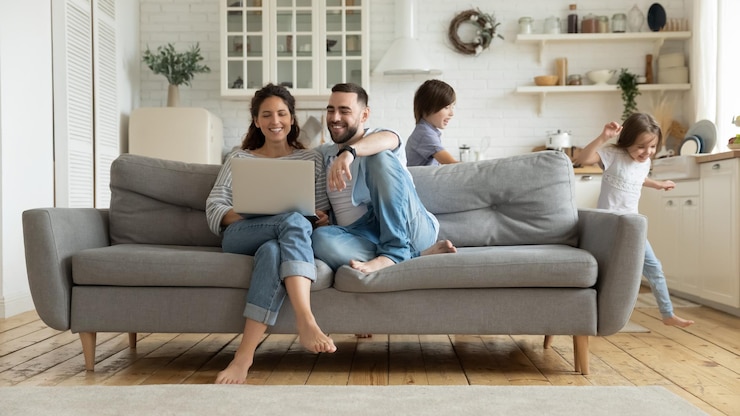 Photo while active kids running parents resting on sofa using laptop