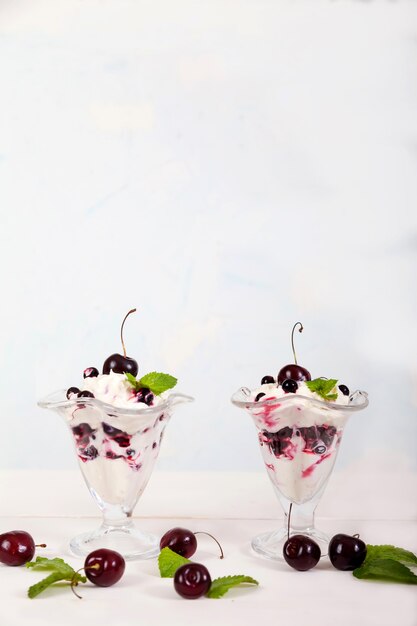 Whipped cream with cherries, currants and mint leaves in glass bowls
