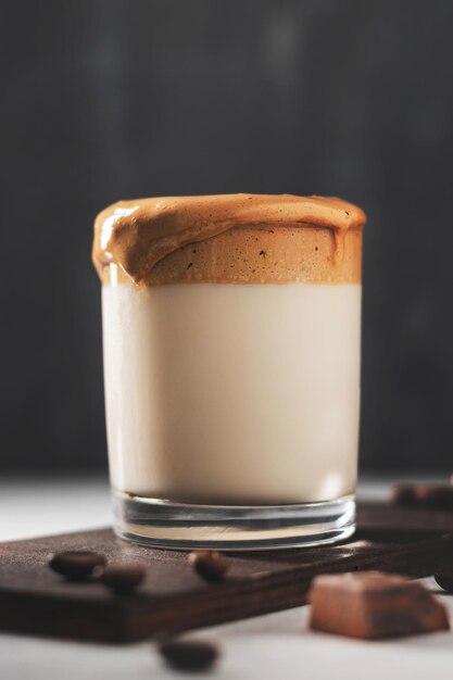 Whipped Dalgona coffee drink in a glass with milk, dark background