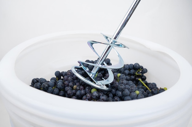 Whipping grapes with a mixer in a barrel the process of making homemade wine