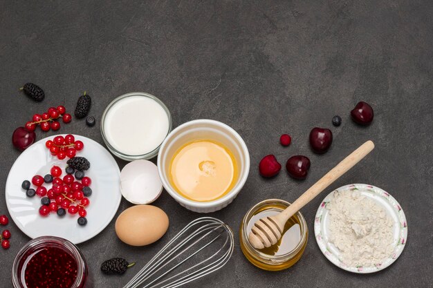 Whisk bowl of broken eggs Flour berry milk butter honey jam Ingredients for cooking breakfast