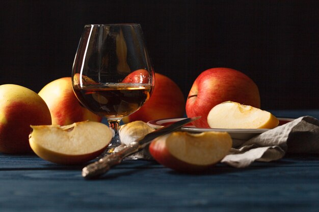 ウイスキーと暗い木製のテーブルの上のリンゴ