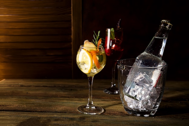 Whiskey based cocktail with glass ice bucket on dark wooden backgorund