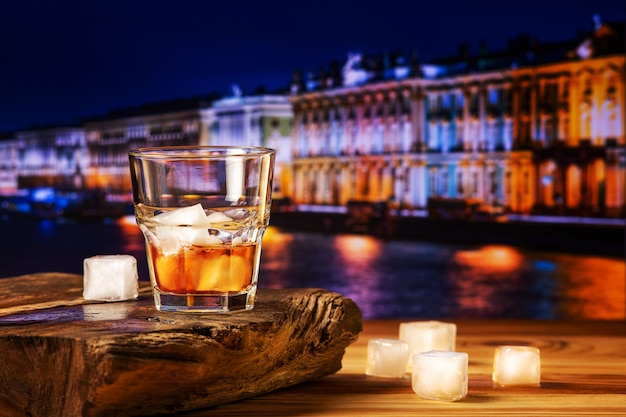 Whiskey cocktail with ice on wooden table