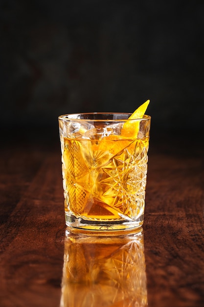 Whiskey cocktail on wooden table with reflection