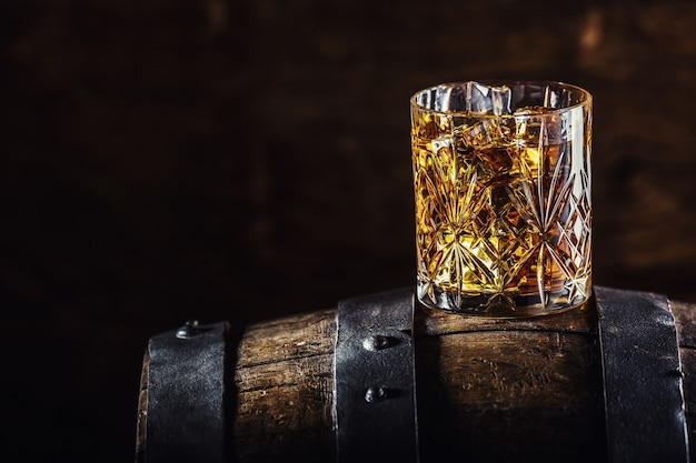 ウイスキードリンク。古い木製の樽にウイスキーのグラス。