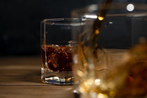Bevande di whisky su legno con cubetti di ghiaccio e spruzzi.
