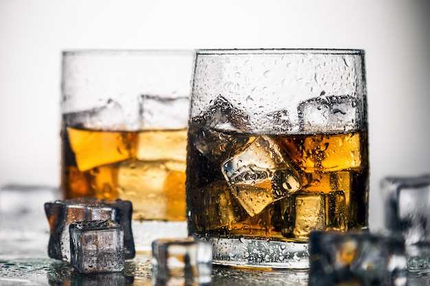 Photo whiskey in a glass with ice on a light background