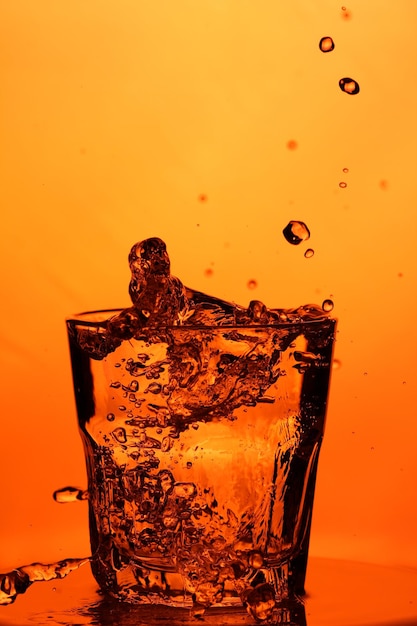 Whiskey glass with water. Glass with water on an orange background