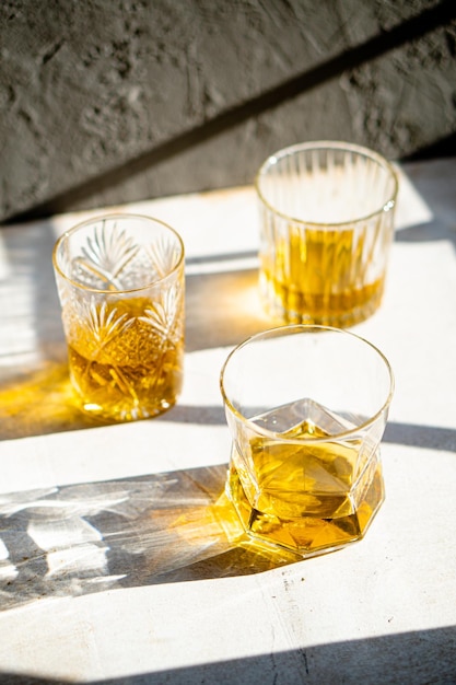 Whiskey in glasses on table in bright sunlight yellow drink