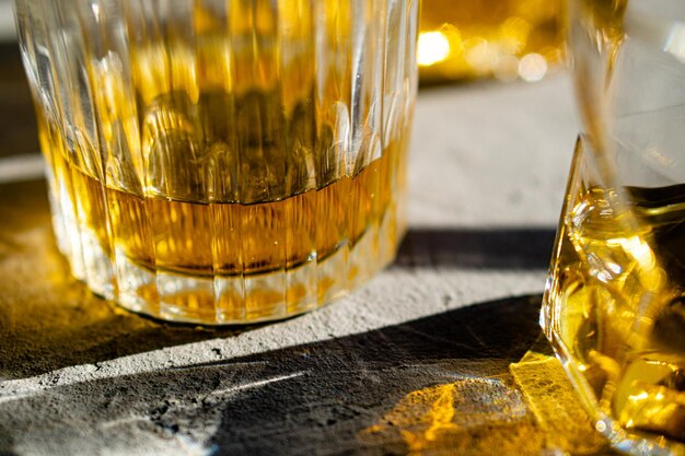 Whiskey in glasses on table in bright sunlight yellow drink