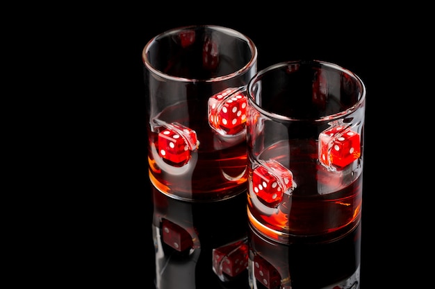 Фото Стаканы для виски с ромом или виски с красными кубиками на фоне темного стекла