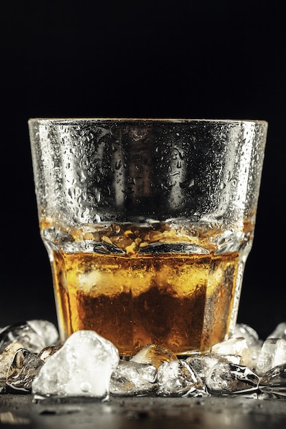 Whiskey and ice on dark background