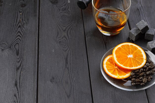 Whiskey or liqueur, coffee beans and orange cut on wooden.