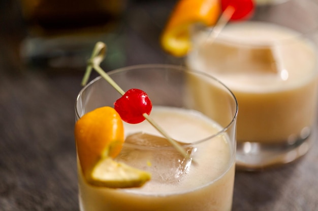 Whiskey sour cocktail garnished with orange and cherry.