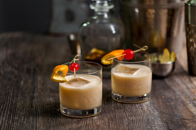 Whiskey sour cocktail garnished with orange and cherry.