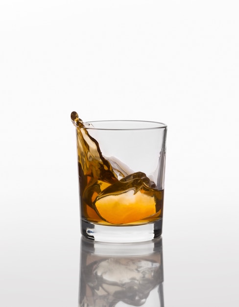 Whiskey splash on elegant glass isolated