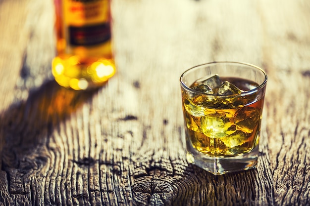 Whiskey. Whiskey drink with ice cubes on old rustic oak table.