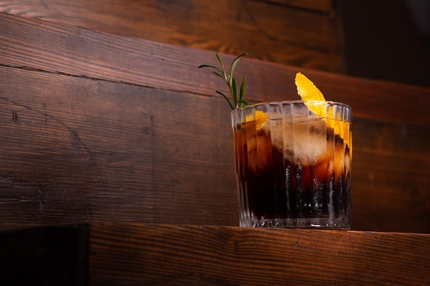 Whiskey with cola on dark wooden board