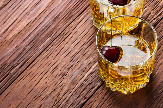 Whiskey with ice and cherry in two glasses