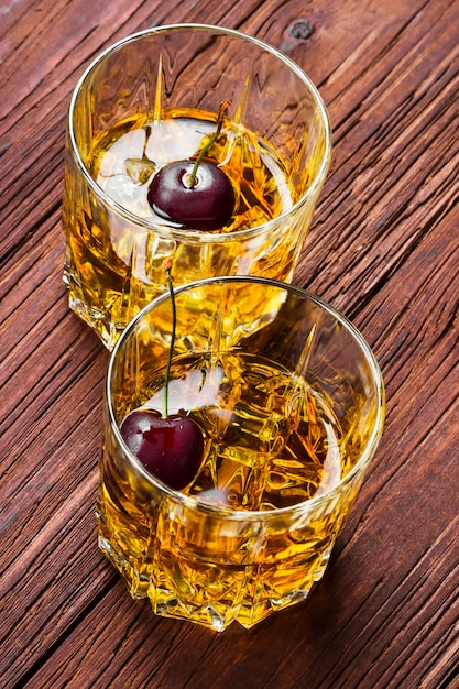 Whiskey with ice and cherry in two glasses