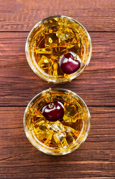 Whiskey with ice and cherry in two glasses