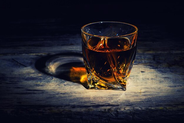 Whiskey with ice cubes on wooden background