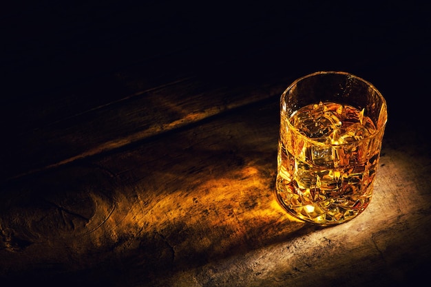 Photo whiskey with ice cubes on wooden background