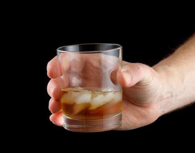 Whiskey with ice in a glass in hand