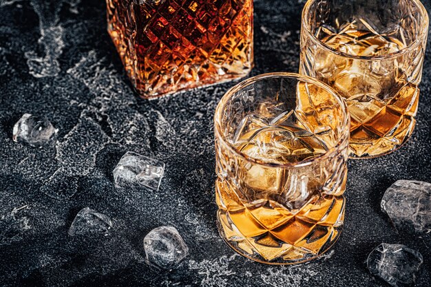 Whiskey with ice on a stone dark background.